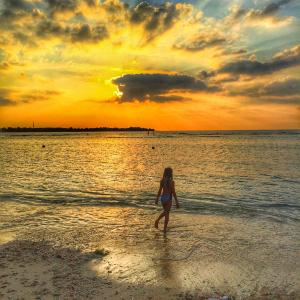 een vrouw die bij zonsondergang op het strand loopt bij Puri Air Beach Resort & Spa in Gili Air