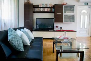 a living room with a black couch and a tv at Kuća za odmor „VILLA MARIJA” in Kostel