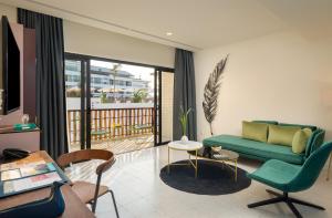 a living room with a green couch and a balcony at The Aviary Hotel in Siem Reap
