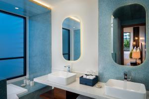 a bathroom with two sinks and two mirrors at The Aviary Hotel in Siem Reap