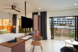 a hotel room with a bed and a desk with a tv at The Aviary Hotel in Siem Reap