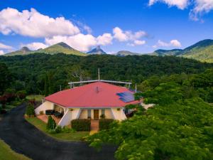 una casa con tetto rosso con montagne sullo sfondo di A view of Mount Warning a Uki