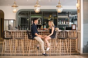 un hombre y una mujer sentados en un banco en un bar en Sawaddi Patong Resort & Spa by Tolani - SHA Extra Plus en Patong Beach