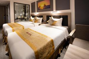 a hotel room with two beds and a chair at Ruby Hotel in Nha Trang