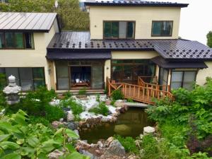 une maison avec un étang en face de celle-ci dans l'établissement Garden House Umenoya Otaru, à Otaru