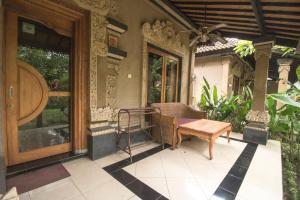 a porch with a table and a bench on a house at Trijaya Guest House Pemuteran in Pemuteran