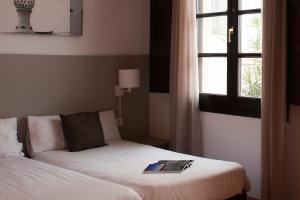 a room with two beds and a window with a book on it at Aspasios Plaza Real Apartments in Barcelona