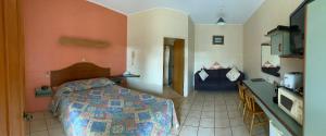a small bedroom with a bed and a kitchen at Curtain Fig Motel in Yungaburra