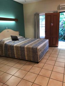 a bedroom with a bed and a tiled floor at Curtain Fig Motel in Yungaburra