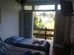 a bedroom with a bed and a large window at Casa Green Vista in Campos do Jordão