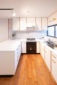 cocina con armarios blancos y suelo de madera en Bettei Gensen-Private Vacation Villa Bettei Gensen, en Yufu