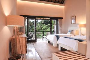 a bedroom with two beds and a balcony at Ijen Resort and Villas - The Hidden Paradise in Banyuwangi