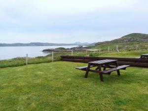a picnic table sitting on the grass near the water at 2 Bayview Bungalow in Poolewe