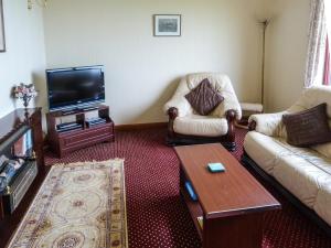 a living room with two chairs and a flat screen tv at 2 Bayview Bungalow in Poolewe