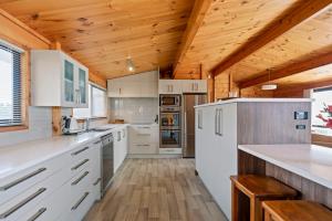 eine Küche mit weißen Schränken und einer Holzdecke in der Unterkunft Oceanside Bach - Mount Maunganui Holiday Home in Mount Maunganui