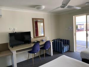 a room with a desk with two chairs and a television at Hervey Bay Motel in Hervey Bay