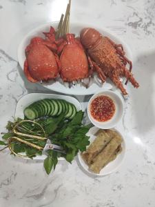 a table with a plate of food with lobster and other foods at Khách Sạn Lý Sơn Phú Sỹ in Ly Son