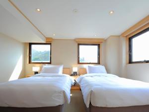 two beds in a room with two windows at T Hotel Ryuoo in Shimotakai