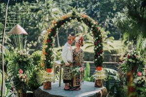 a bride and groom standing under an arch at a wedding at Pondok Sebatu Villa in Tegalalang