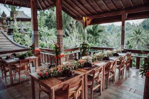 uma longa mesa de madeira com flores num pátio em Pondok Sebatu Villa em Tegalalang