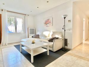 Appartement devant la plage في روساس: غرفة معيشة مع أريكة بيضاء وطاولة