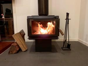 a stove with a fire in a living room at Witches Falls Cottages in Mount Tamborine