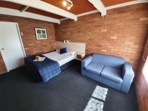 a room with a bed and a couch and a chair at Red Chief Motel in Gunnedah