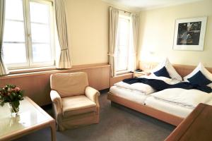 ein Schlafzimmer mit einem Bett, einem Stuhl und einem Fenster in der Unterkunft Hotel Alte Post in Mindelheim