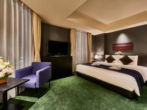 a bedroom with a large bed and a purple chair at The Gate Hotel Asakusa Kaminarimon by Hulic in Tokyo