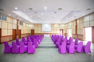 une salle de conférence avec des chaises violettes et un écran dans l'établissement Xanadu Beach Resort, à Ko Larn