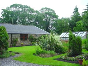 a garden with a house and a yard with plants at Blackaddie House Hotel in Sanquhar