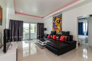 sala de estar con sofá negro y TV en Orchid Paradise Homes 312, en Hua Hin
