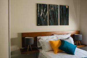 a bedroom with a bed with three paintings on the wall at casa AGAVE x Santiago de Tequila in Tequila +7 photos