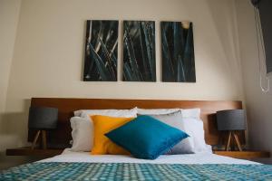 a bedroom with a bed with three paintings on the wall at casa AGAVE x Santiago de Tequila in Tequila