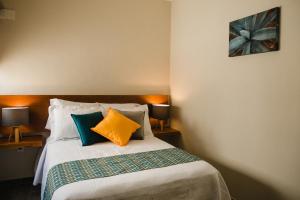 a bedroom with a bed with colorful pillows at casa AGAVE x Santiago de Tequila in Tequila