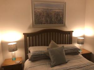 a bedroom with a bed with two lamps and a painting at SOLACE COTTAGE in Bunavoneader