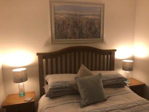 a bedroom with a bed with two lamps and a painting at SOLACE COTTAGE in Bunaveneadar