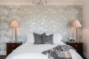 a bedroom with a white bed with two lamps at Cottage 103 in Waikanae