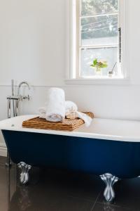 a bathroom with a blue tub with a window at Cottage 103 in Waikanae