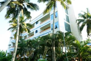 un edificio con palmeras delante en Ocean Bay Ayurvedic Beach Resort, en Kovalam