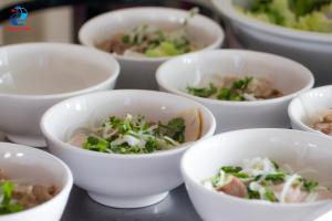 a group of white bowls filled with food on a table at HỒ MÂY PARK Vũng Tàu Khách Sạn - Resort in Vung Tau