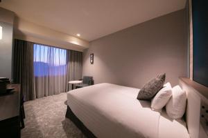 長崎市にあるホテルJALシティ長崎のベッドと大きな窓が備わるホテルルームです。