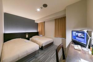 a hotel room with two beds and a desk with a television at Ginza Capital Hotel Akane in Tokyo