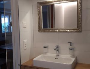 uma casa de banho com um lavatório branco e um espelho. em Appartement Säntisblüte em Rehetobel