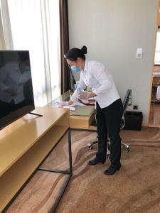 a woman wearing a face mask standing at a desk at Shenzhen Futian Wyndham Grand in Shenzhen
