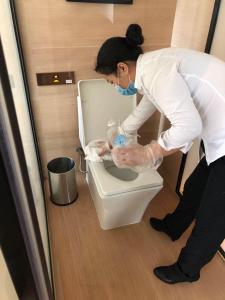 a woman is looking at a toilet in a bathroom at Shenzhen Futian Wyndham Grand in Shenzhen