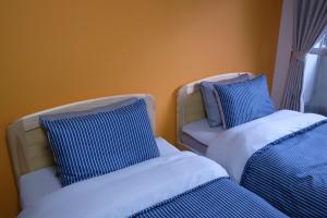Cette chambre comprend 2 lits avec des oreillers bleus et blancs. dans l'établissement KYOTO SANJO Inn 京都三条イン, à Kyoto