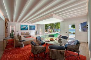 a living room with a glass table and chairs at Emerald Maldives Resort & Spa-Deluxe All Inclusive in Raa Atoll