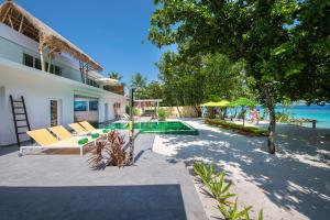 a house with a swimming pool next to the ocean at Emerald Maldives Resort & Spa-Deluxe All Inclusive in Raa Atoll