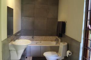 a bathroom with a tub and a toilet and a sink at Lucky Bean Guesthouse in Johannesburg